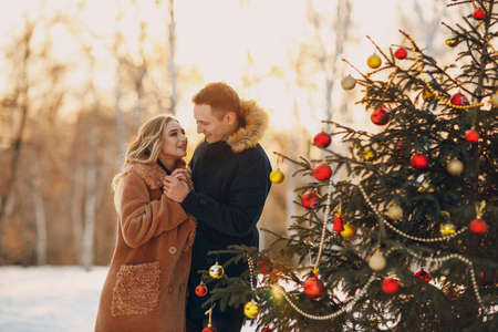 Young adult couple decorates christmas tree in winter forest. New year pine holiday party celebration conceptの写真素材