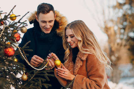 Young adult couple decorates christmas tree in winter forest. New year pine holiday party celebration conceptの写真素材