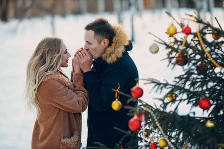 Young adult couple decorates christmas tree in winter forest. New year pine holiday party celebration conceptの写真素材