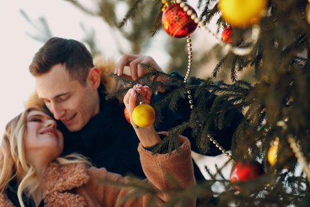 Young adult couple decorates christmas tree in winter forest. New year pine holiday party celebration conceptの写真素材