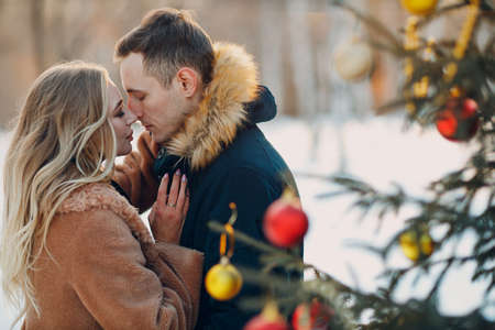 Young adult couple decorates christmas tree in winter forest. New year pine holiday party celebration conceptの写真素材