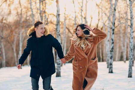 Loving young couple walking playing and having fun in winter forest park.の写真素材