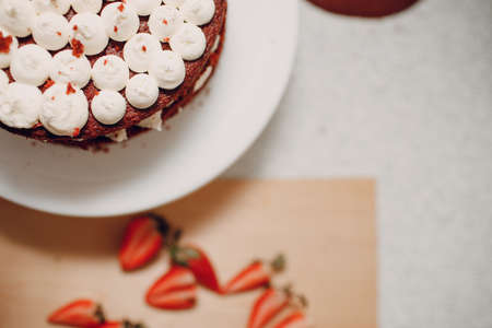 Making delicious red velvet cake. Cooking and decorating dessert with cream cheese and strawberry.の写真素材