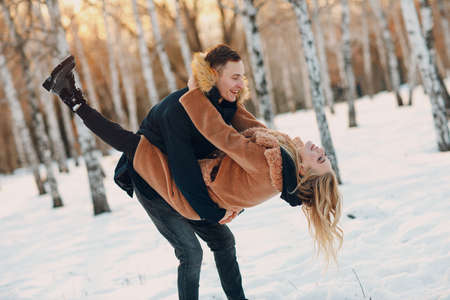 Loving young couple hugging and having fun in winter forest park.の写真素材