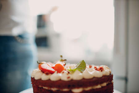 Making delicious red velvet cake. Cooking and decorating dessert with cream cheese, mint and strawberry.の写真素材