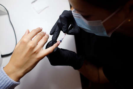 Manicure process female hands finger nails polish. Beautician in gloves at nail salonの写真素材