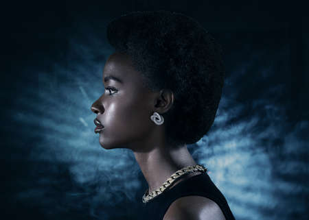 Young black woman profile beauty portrait on dark night club background with blue light rays and...