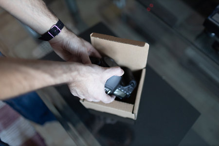 Adult man small business owner packing order box package shipping to customer. Entrepreneur packaging camera in box for delivery at home.の写真素材