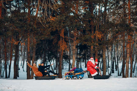 Ded Moroz riding snowmobile couple in love in the winter forest.の写真素材