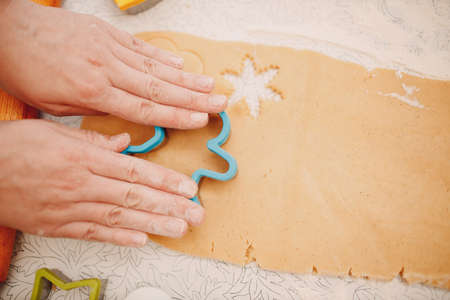 Woman hands form molds cutters ginger dough and makes delicious christmas ginger cookies. Cooking and decorating christmas dessert flourの写真素材