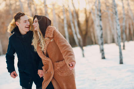 Loving young couple man and young woman walking and having fun in winter forest park.の写真素材