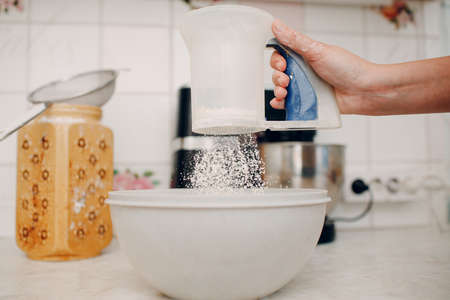Pastry chef sift pours flour makes cake. Cooking and preparing dessert.の写真素材