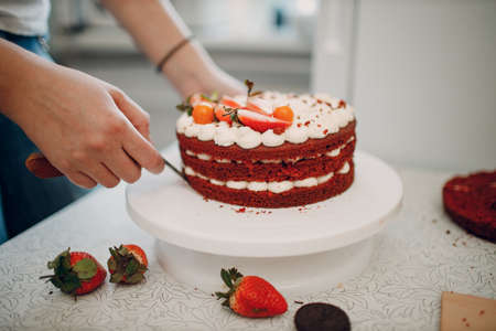 Making delicious red velvet cake. Cooking and decorating dessert with cream cheese, mint and strawberry berry.の写真素材