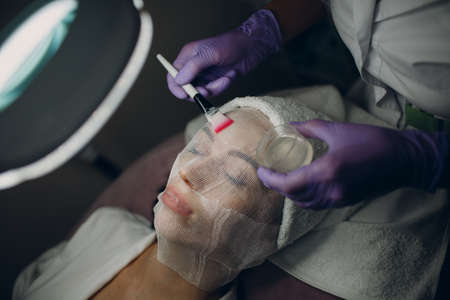 Paraffin Face Mask gauze bandage Therapy Young Woman Receiving Facial Skin Care Treatment. Beautician Pouring Wax Applying.の写真素材