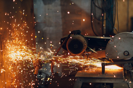 Metal processing with big compound mitre saw with circular blade. Sparks in metalworking at factory