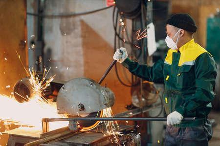 Metal processing with big compound mitre saw with circular blade. Sparks in metalworking at factory