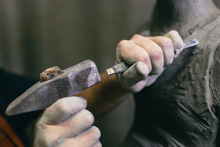 Man sculptor creates sculpt bust human woman sculpture with hammer. Statue craft creation workshop.の写真素材