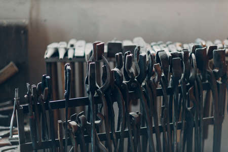 Blacksmith forge oven with hot flame. Smith heating iron piece of steel in fire of red-hot forge with toolsの写真素材