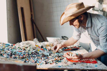 Man mosaics master chooses select smalt glass pieces for mosaic panel. Male mosaicist at workの写真素材