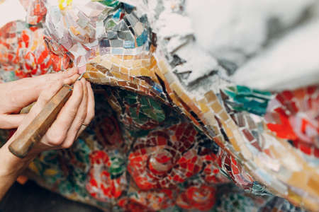 Man mosaics master in hat making smalt glass mosaic panel. Male mosaicist at workの写真素材