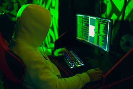 Hacker in hoodie working hacks code site on personal computer. War and cyber attack conceptの写真素材
