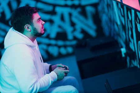 Guy young adult man gamer playing video game on game console at computer gaming club or homeの素材 [FY310188718426]