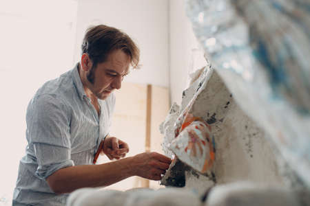 Workplace mosaics master making smalt glass mosaic panel. Man mosaicist at work