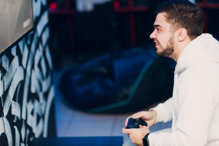 Guy young adult man gamer playing video game on game console at computer gaming club or home