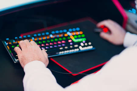 Guy playing gaming game on computer keyboard close up hands at club.
