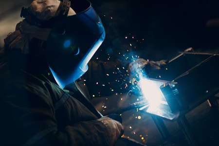 Welder welding metal steel industrial part construction on factory.