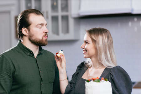 Pastry chef confectioner young caucasian woman give try husband boyfriend man taste of cake on...