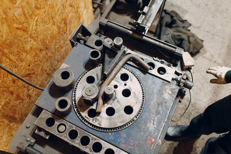 Worker at factory with industrial machine for bending of metal pipes.の写真素材
