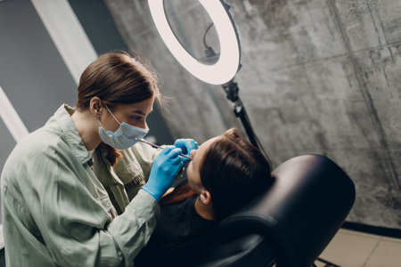Young woman doing piercing at beauty studio salonの写真素材