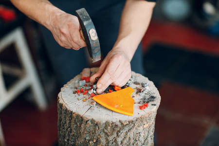 Craftsman cutting breaking smalt glass with hammer for mosaic artwork in workshop.の写真素材