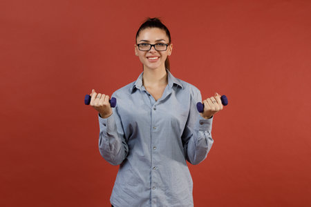 Successful young modern businesswoman in blue shirt warming up with dumbbells at office while working, Business, work, woman and sport fitness workout exercise conceptの写真素材