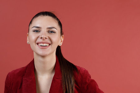 Young smiling caucasian 30s woman in red velvet jacket face portrait looking cameraの写真素材