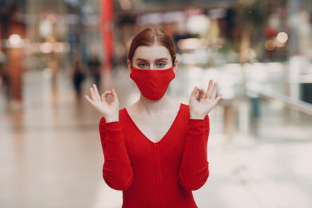 Portrait of young woman in protective medical face mask at shopping mall. Yoga, calm, zen and meditation a covid-19 pandemia concept.の写真素材