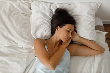Healthy young woman dressing nightie lying on bed in bedroom.の写真素材