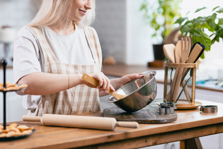 Pastry chef confectioner young caucasian woman with kitchen bowl on kitchen table. Cakes dessert makingの写真素材