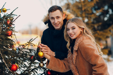 Young adult couple decorates christmas tree in winter forest. New year pine holiday party celebration conceptの写真素材