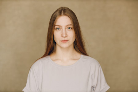 Portrait of young caucasian woman looking at camera against beige backgroundの写真素材