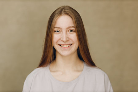 Portrait of young smile caucasian woman looking at camera against beige backgroundの写真素材