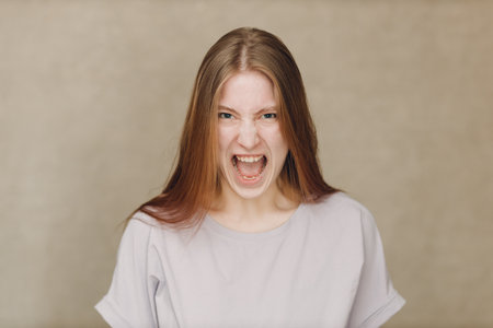 Portrait of young actress caucasian woman looking at camera against beige backgroundの写真素材