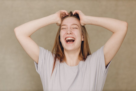 Portrait of young happy actress laughing caucasian woman looking at camera against beige backgroundの写真素材
