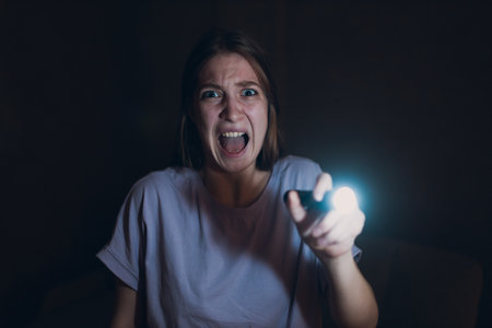 Woman scared holding hand flashlight in darkness and afraid of violence criminal robberyの写真素材