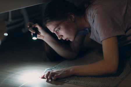 Woman young holding hand flashlight in darkness and search dirt spot on carpetの写真素材
