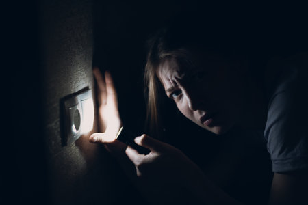 Woman young holding hand flashlight in darkness. Disconnecting home electricity and changing electrical switchの写真素材