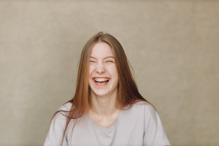 Portrait of young happy laughing caucasian woman at casting movie auditions against beige backgroundの写真素材