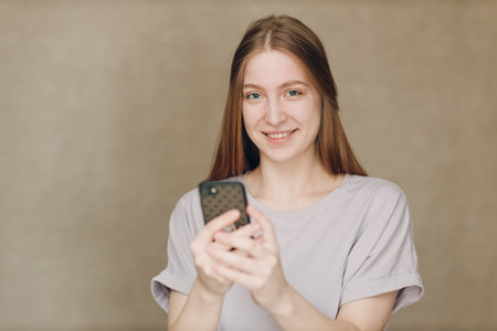 Young woman using mobile phone at brown backgroundの写真素材