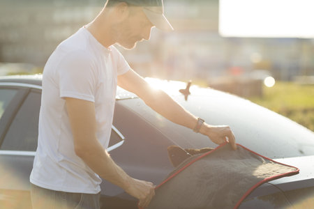 Worker washing car at car wash and wipe vehicle with microfiber towel ragの写真素材